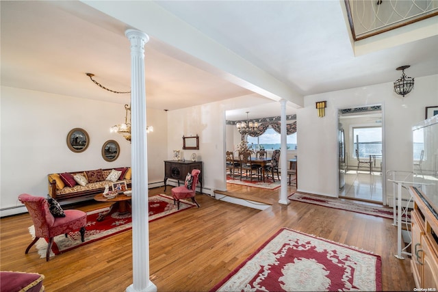 living room featuring ornate columns, a notable chandelier, and hardwood / wood-style flooring