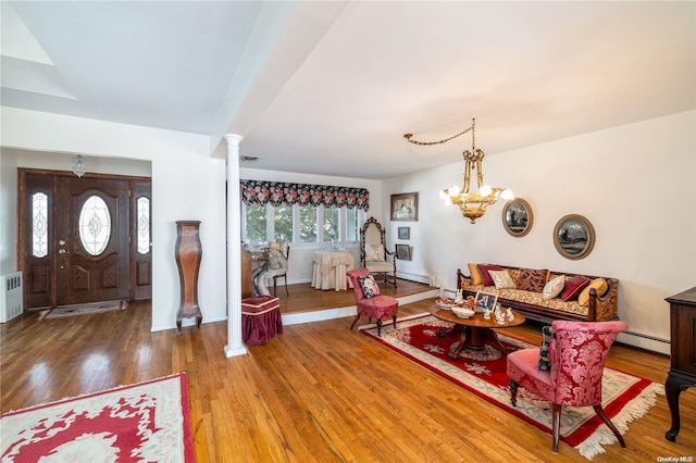 living room featuring hardwood / wood-style floors, decorative columns, an inviting chandelier, and a baseboard radiator