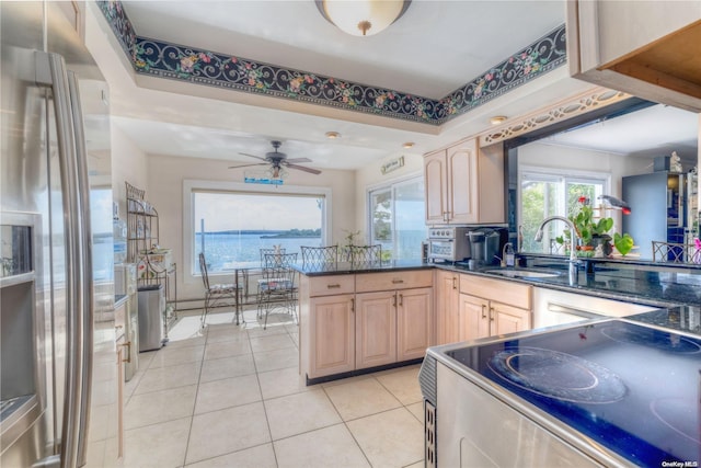 kitchen with stove, light brown cabinetry, sink, light tile patterned floors, and stainless steel fridge with ice dispenser