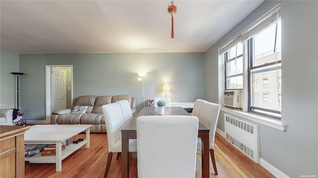 dining area with radiator heating unit, a healthy amount of sunlight, and hardwood / wood-style floors