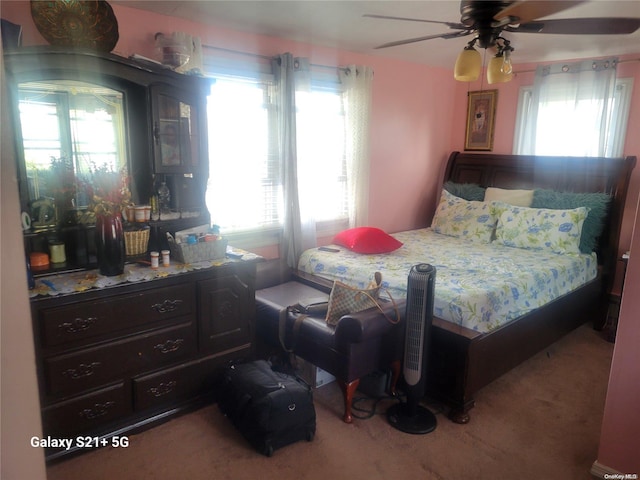 bedroom featuring ceiling fan, light carpet, and multiple windows