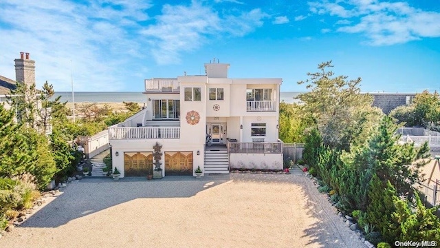 view of front of house featuring a garage, a balcony, and a water view