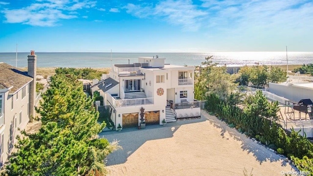 view of front of house featuring a water view, a balcony, and a view of the beach