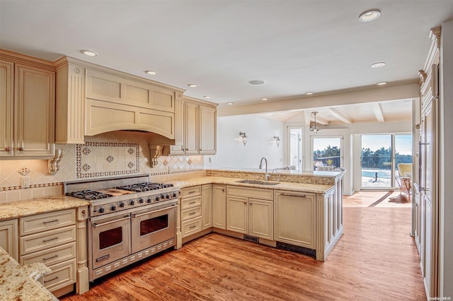 kitchen with cream cabinetry, beam ceiling, double oven range, and sink