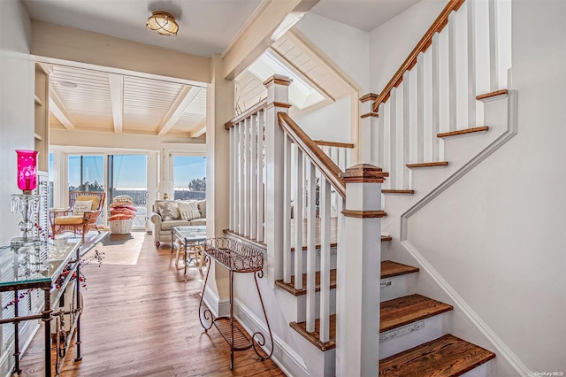 staircase featuring wood-type flooring, wood ceiling, and beam ceiling