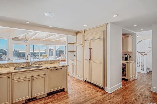 kitchen with cream cabinetry, beam ceiling, ceiling fan, and sink