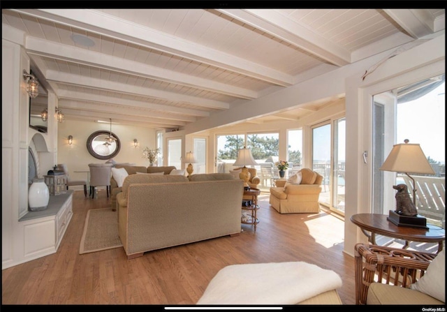 living room with beamed ceiling, a chandelier, and light wood-type flooring