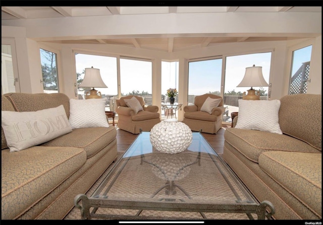 living room featuring beamed ceiling, hardwood / wood-style flooring, and a wealth of natural light