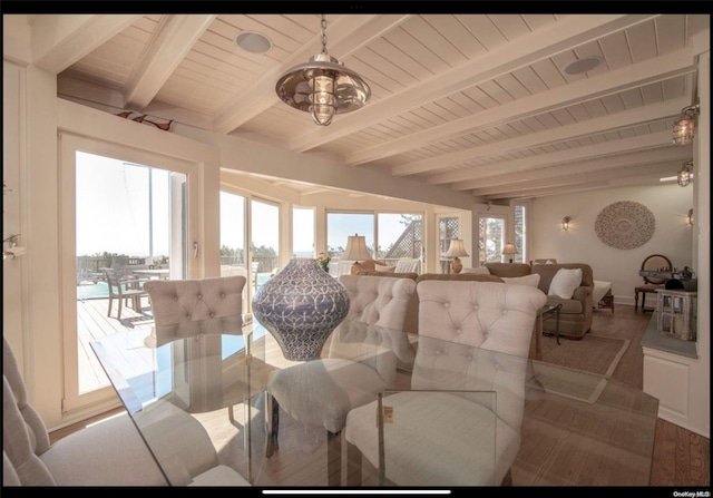 sunroom / solarium featuring beamed ceiling and a chandelier