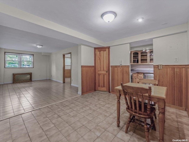 dining space featuring light tile patterned floors and wooden walls