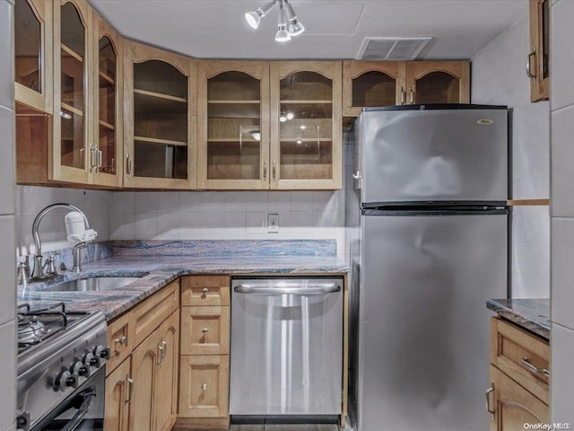 kitchen featuring decorative backsplash, dark stone countertops, sink, and appliances with stainless steel finishes