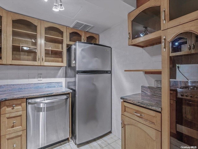 kitchen featuring stone counters, light tile patterned floors, backsplash, and appliances with stainless steel finishes