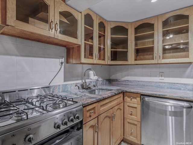 kitchen featuring backsplash, stainless steel appliances, dark stone counters, and sink