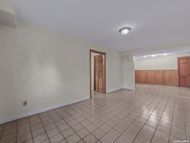 unfurnished room with light tile patterned floors and wooden walls