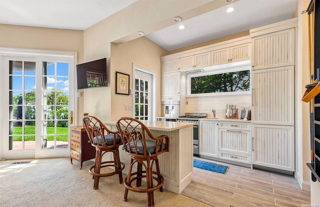 kitchen featuring a kitchen bar, gas range, a wealth of natural light, and light hardwood / wood-style floors