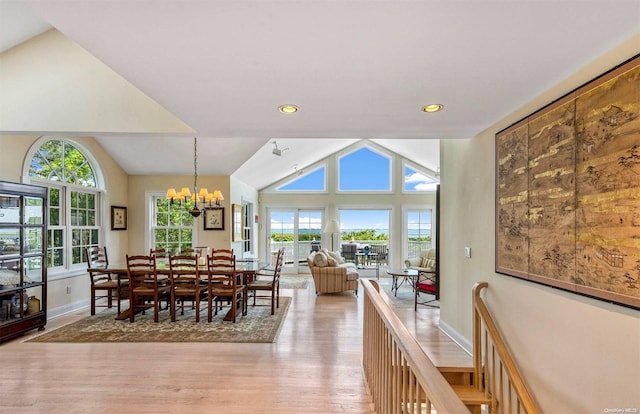 dining space featuring plenty of natural light, a chandelier, lofted ceiling, and light wood-type flooring