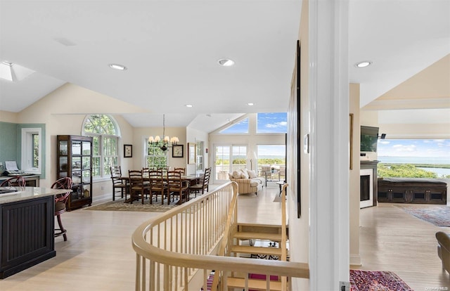 staircase with hardwood / wood-style flooring, vaulted ceiling, and an inviting chandelier