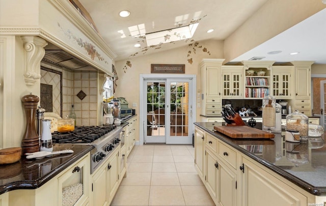 kitchen with stainless steel gas stovetop, french doors, vaulted ceiling with skylight, light tile patterned floors, and cream cabinetry