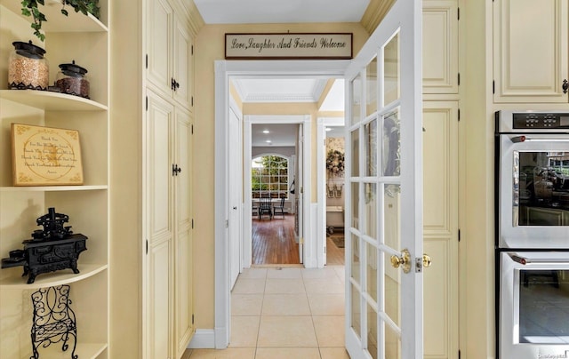 corridor with french doors, light wood-type flooring, and ornamental molding