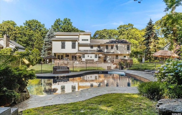 back of property with a gazebo, a patio, a fenced in pool, and a lawn