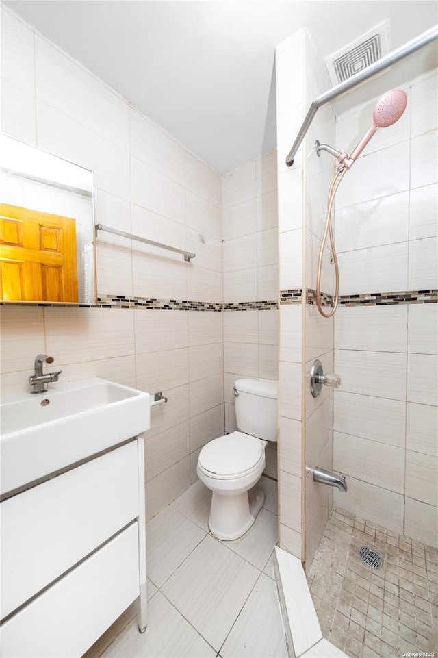 bathroom with tile patterned flooring, vanity, tile walls, and toilet