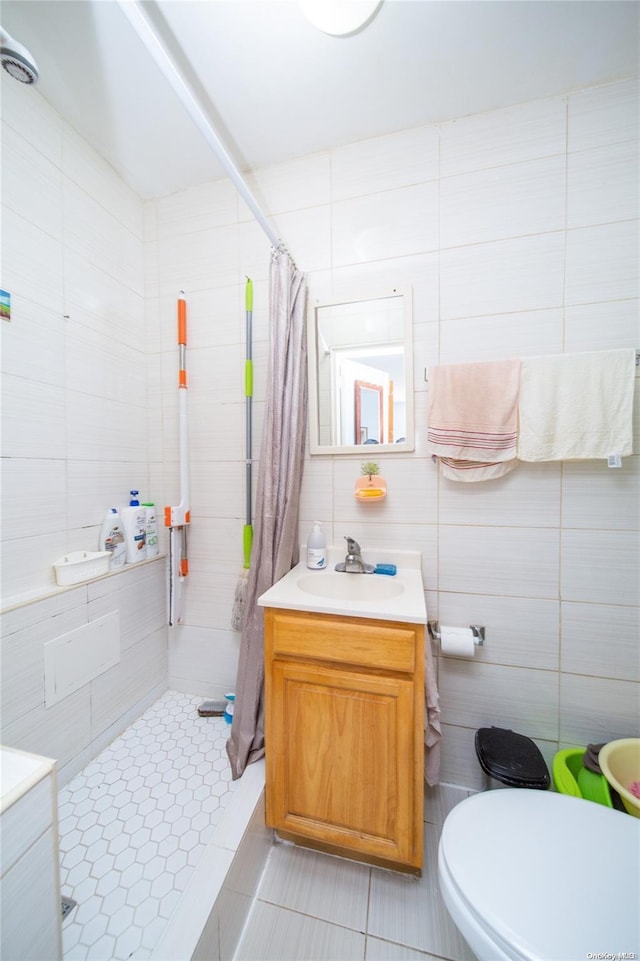 bathroom with curtained shower, tile patterned flooring, toilet, vanity, and tile walls