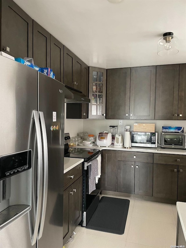 kitchen with dark brown cabinets, stainless steel appliances, and light tile patterned floors