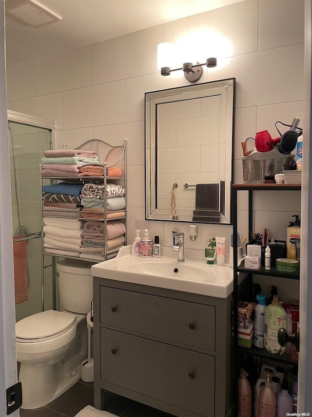 bathroom featuring vanity, toilet, tile walls, and walk in shower