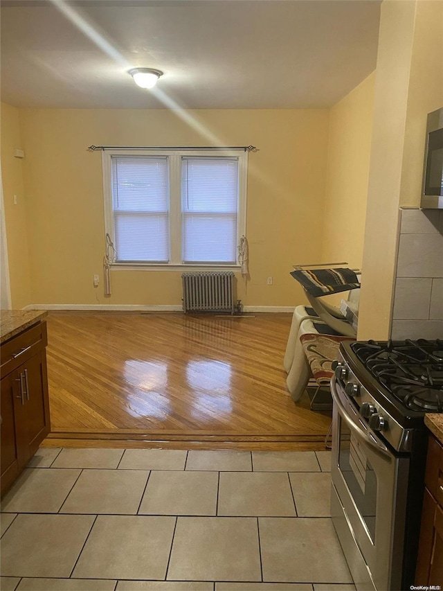 kitchen featuring dark brown cabinetry, light wood-type flooring, stainless steel appliances, and radiator