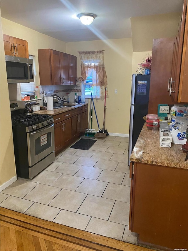 kitchen with light stone countertops, appliances with stainless steel finishes, and sink