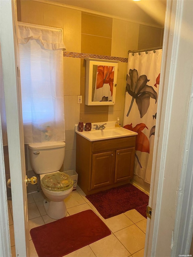 bathroom featuring tile patterned flooring, vanity, toilet, and tile walls