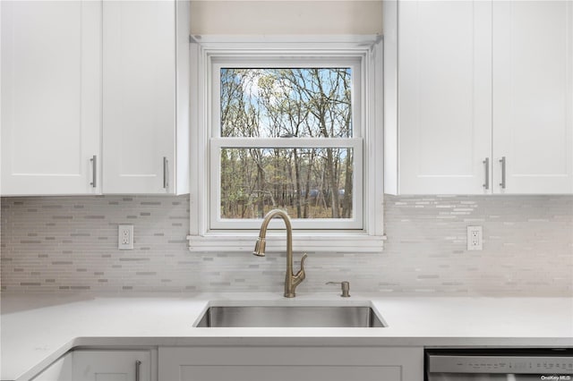 kitchen featuring backsplash, white cabinetry, sink, and dishwasher