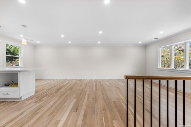 spare room featuring ornamental molding, a wealth of natural light, and light hardwood / wood-style flooring