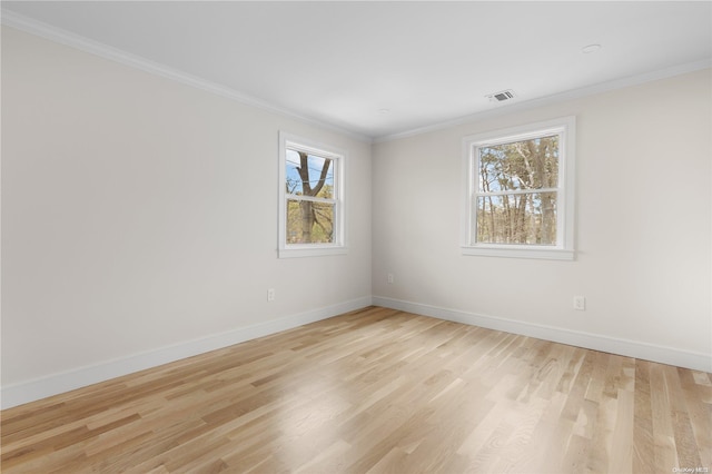 empty room with light hardwood / wood-style floors, a wealth of natural light, and ornamental molding