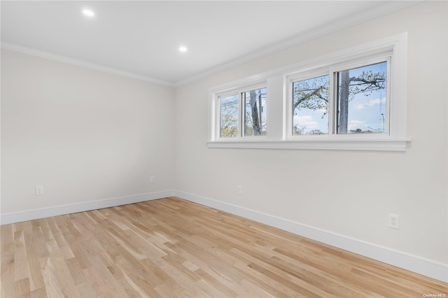 spare room featuring light wood-type flooring and crown molding