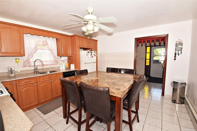 kitchen featuring a kitchen breakfast bar, sink, light tile patterned floors, white refrigerator, and a baseboard radiator