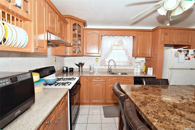 kitchen featuring sink, light stone counters, decorative backsplash, light tile patterned flooring, and black appliances