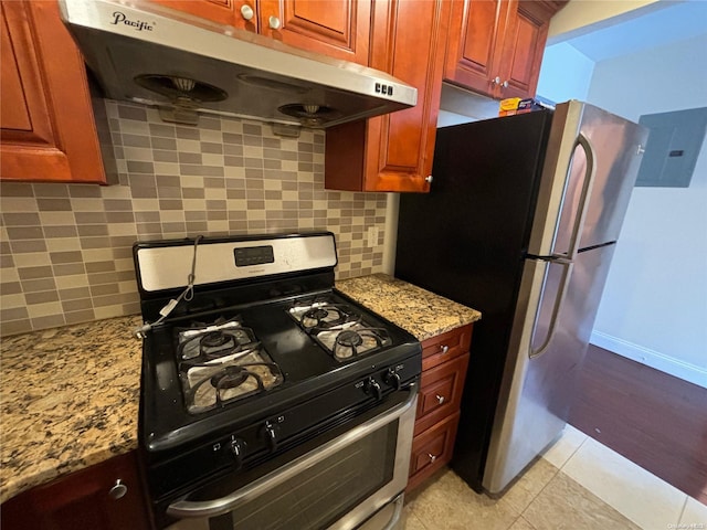 kitchen featuring decorative backsplash, appliances with stainless steel finishes, extractor fan, and light stone counters