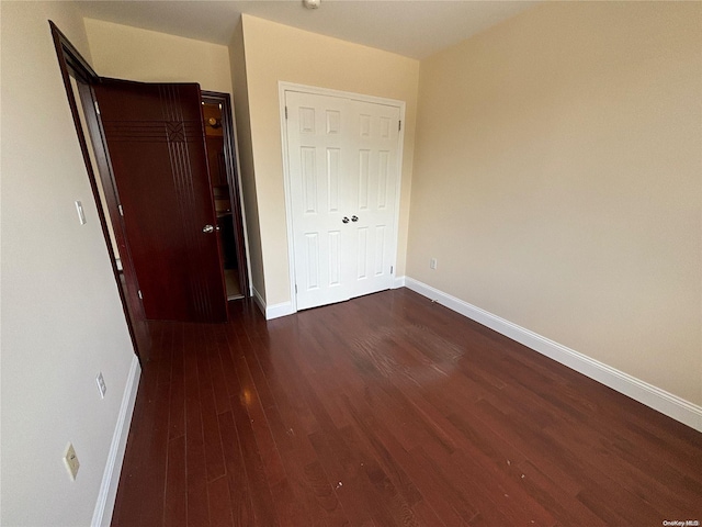 unfurnished bedroom with dark hardwood / wood-style flooring and a closet