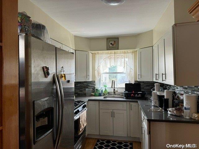 kitchen with sink, dark wood-type flooring, stainless steel appliances, backsplash, and white cabinets