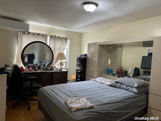 bedroom featuring hardwood / wood-style flooring and a wall unit AC