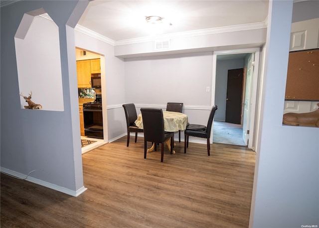 dining space featuring wood-type flooring and ornamental molding