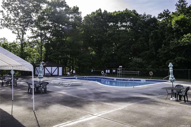 view of swimming pool with a storage unit and a patio