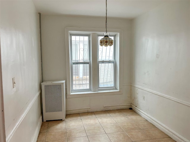 unfurnished dining area with light tile patterned flooring and radiator heating unit