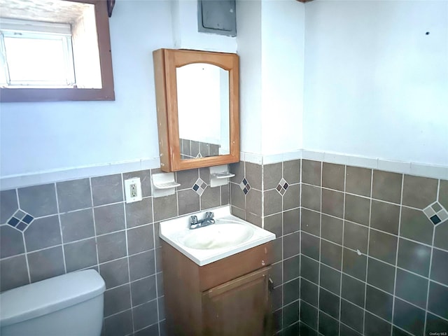 bathroom with vanity, tile walls, and toilet