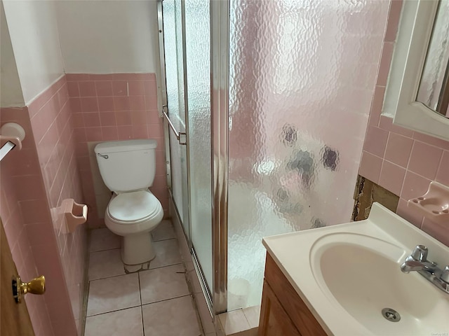 bathroom featuring toilet, a shower with shower door, and tile walls