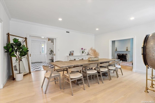 dining room with crown molding and light wood-type flooring