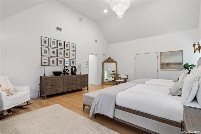 bedroom featuring high vaulted ceiling, wood-type flooring, and a notable chandelier