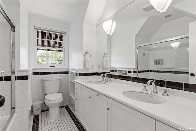 bathroom featuring tile patterned floors, vanity, tile walls, toilet, and lofted ceiling