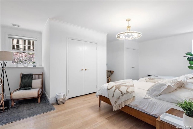 bedroom featuring a chandelier, light hardwood / wood-style floors, and ornamental molding